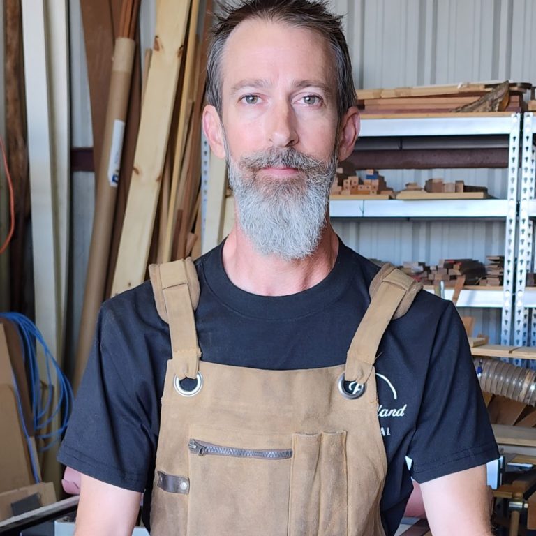 Kevin Pruitt in the Studio Kevin Pruitt wearing a work apron and standing in his woodworking studio.