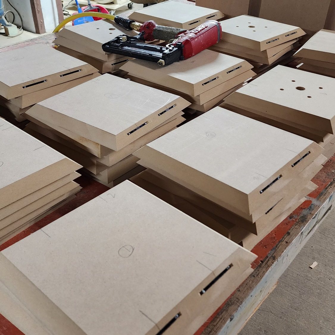 CNC-Cut Panels Light-colored square panels with routed slots and cutouts arranged across a work surface.
